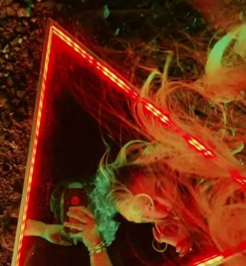 Model posing inside a red LED triangle mirror for a Puma Middle East shoot